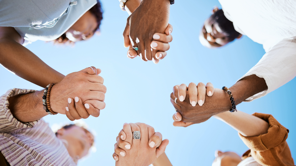 Group of people of different ethnicities and skin tones holding hands in a circle