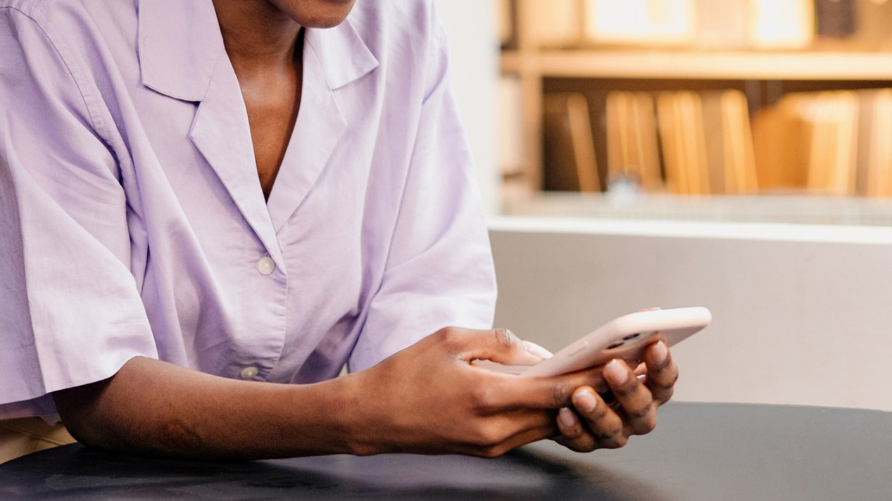 Person at a table holding and looking at a smartphone