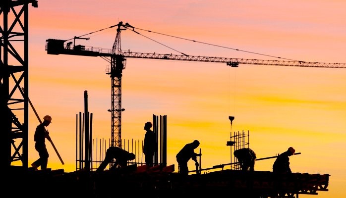 Construction workers building at sunset