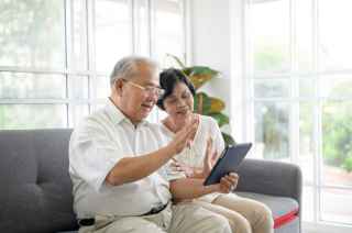 Asian couple sitting at home scrolling through a tablet together