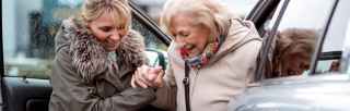 Older daughter helping mother out of the car