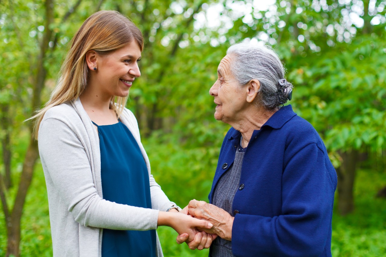 woman gently holding older adult's hand