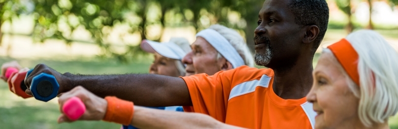 group of older adults lifting dumbbells outdoors