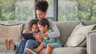 Mother and kids sitting on a couch watching a video on an ipad together