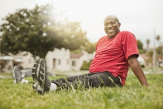 Man sitting in grass wearing exercise clothes