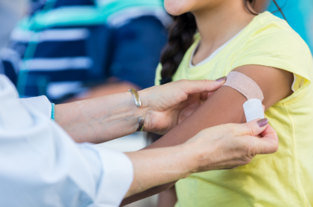 A medical provider putting a band-aid on a child's arm.