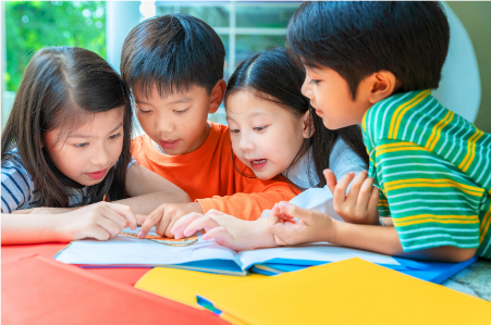 A group of young children looking at educational materials.