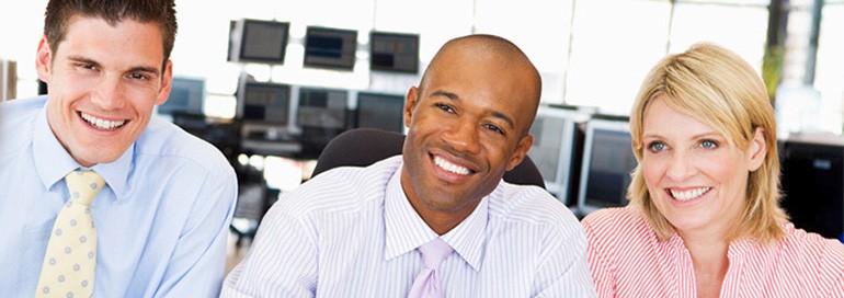 Three business professionals smiling and looking forward, appearing ready to meet someone.