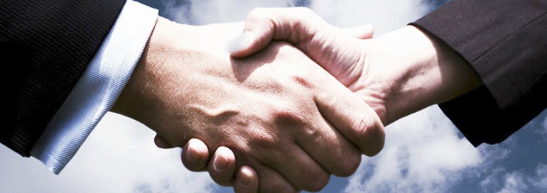 Two professionals shaking hands in a formal setting.