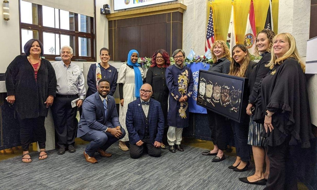 A large group of commissioners gathered together holding an award plaque