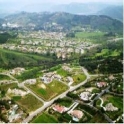 A residential valley with scattered homes, surrounded by green open space and distant mountains.