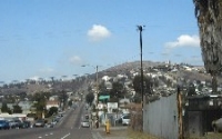 Busy road with several cars driving on it and a mountainous landscape in the background