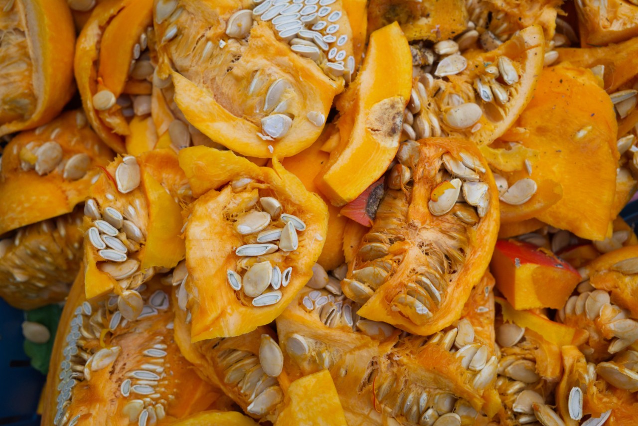 Organic waste, heap of fresh raw sliced ripe pumpkins and pumpkin seeds.