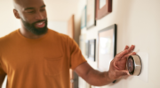 Individual changing the setting on a smart thermostat on the wall