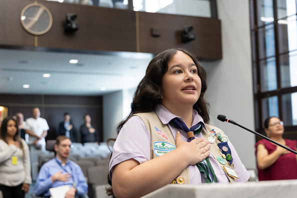 a girl scout and others pledge allegiance at the county chambers